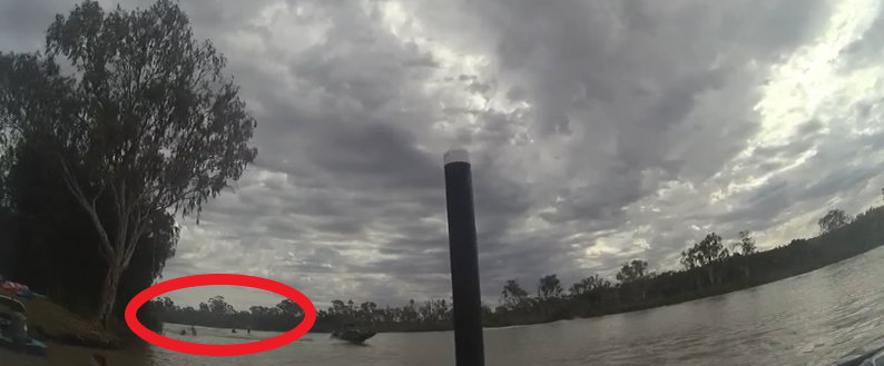 Body cam camera view of ski boat with kneeboarders near boat ramp and bank of river