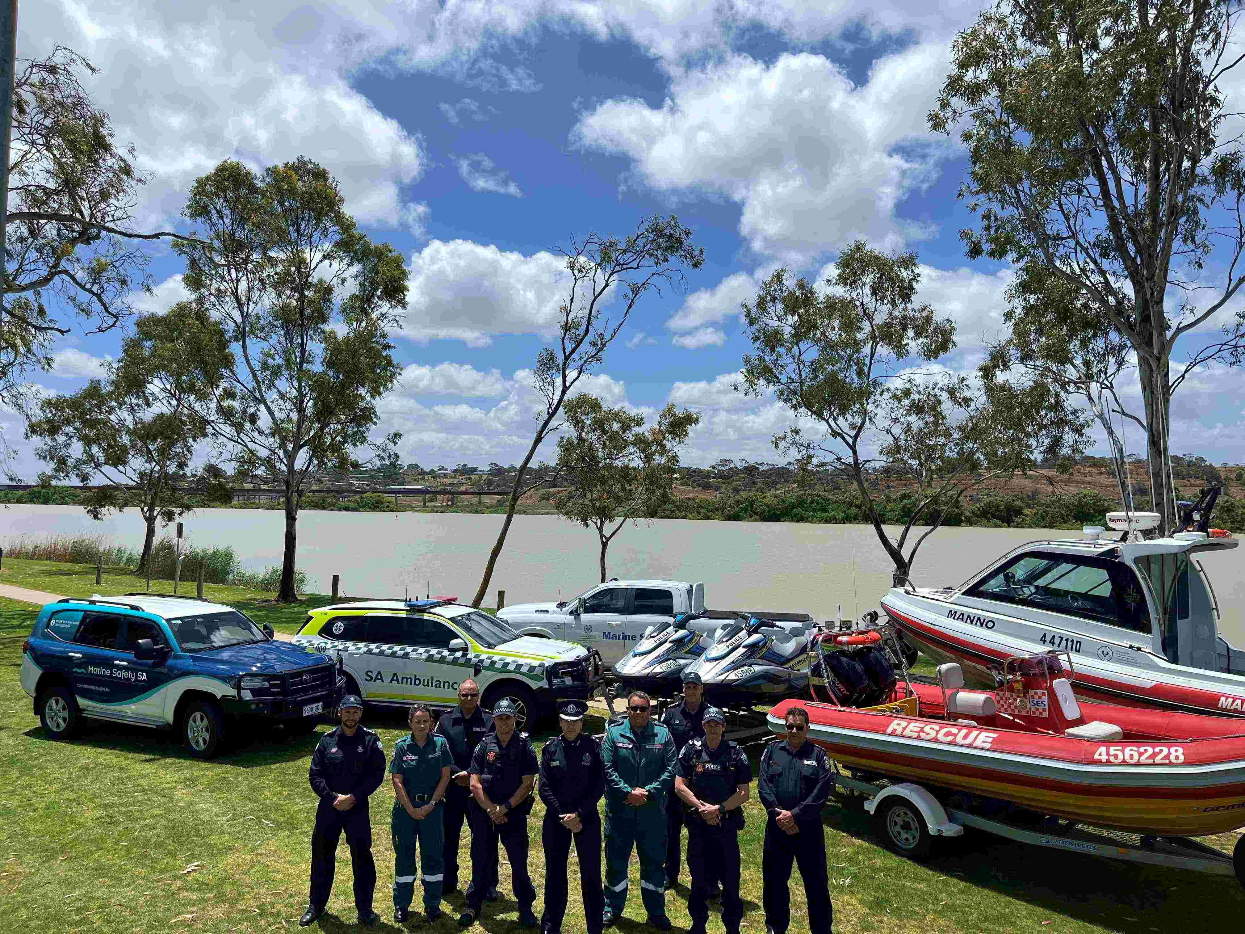 The photo is members from Marine Safety SA, SA Police, State Emergency Services and South Australian Ambulance Services promoting safety on the River Murray. All members are standing together in front of all emergency services vehicles and vessels on the River Murray.