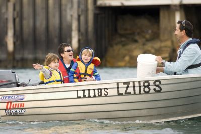 Man and lady and two children in tinny on water wearing lifejackets