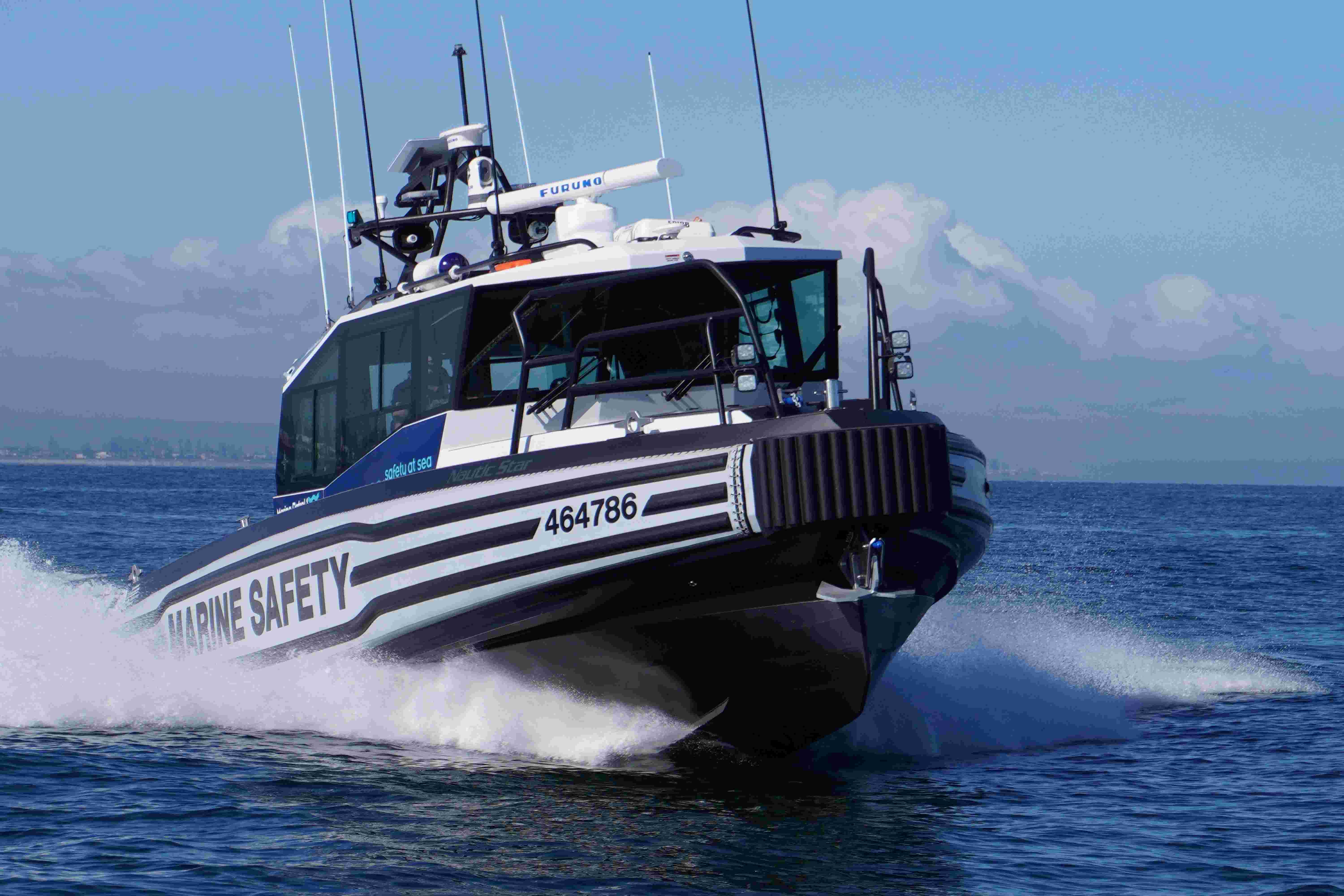 Marine Safety Vessel gliding through the ocean. In the background is Adelaide metro coast and partially cloudy sky.