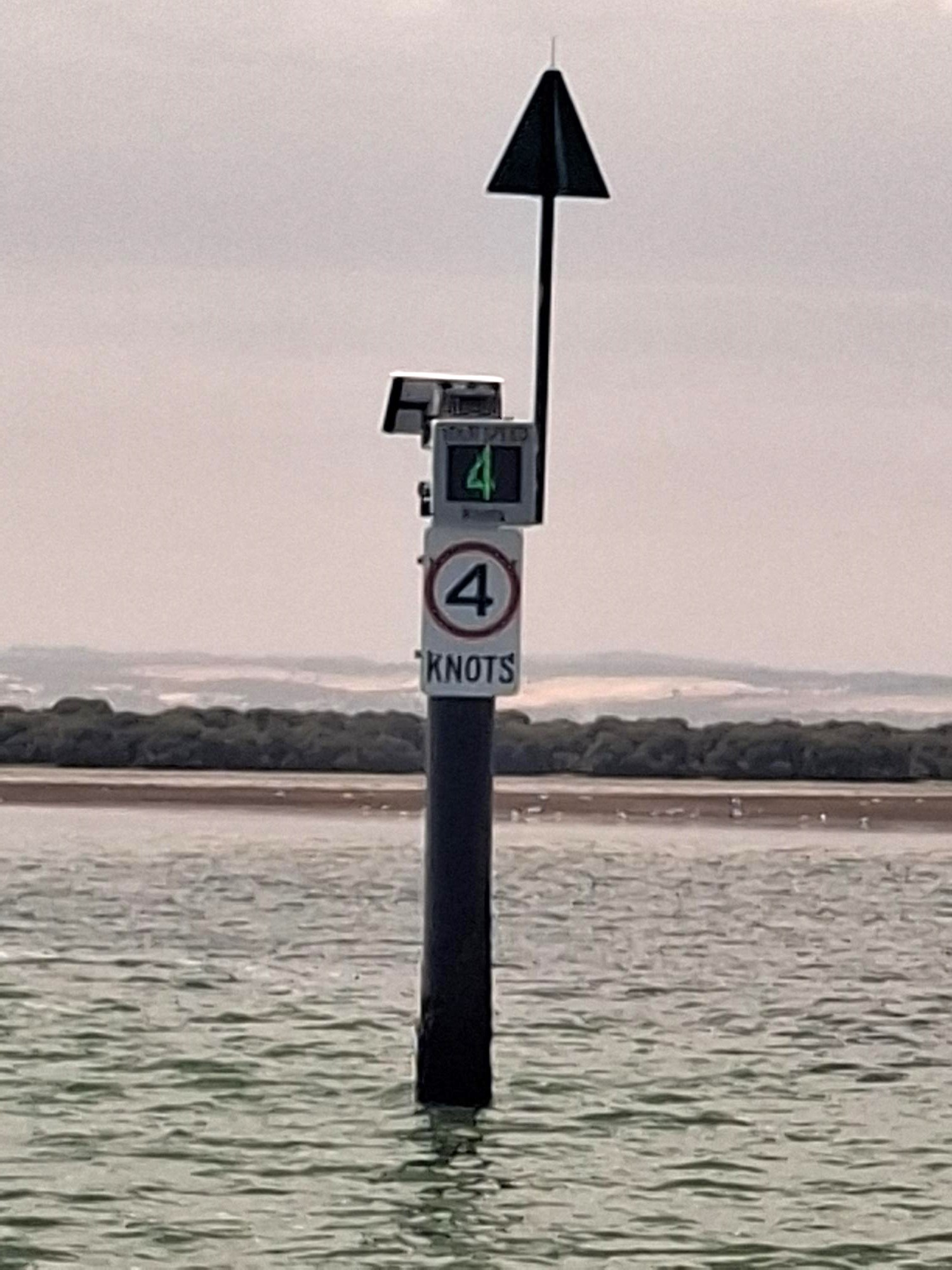 Pictured is our new electronic signs that have been installed to show people the speed limit they are doing in a 4knot zoned area of water. This is placed on a beacon pole in the water. The photo shows a cloudy summers day with calm waters.