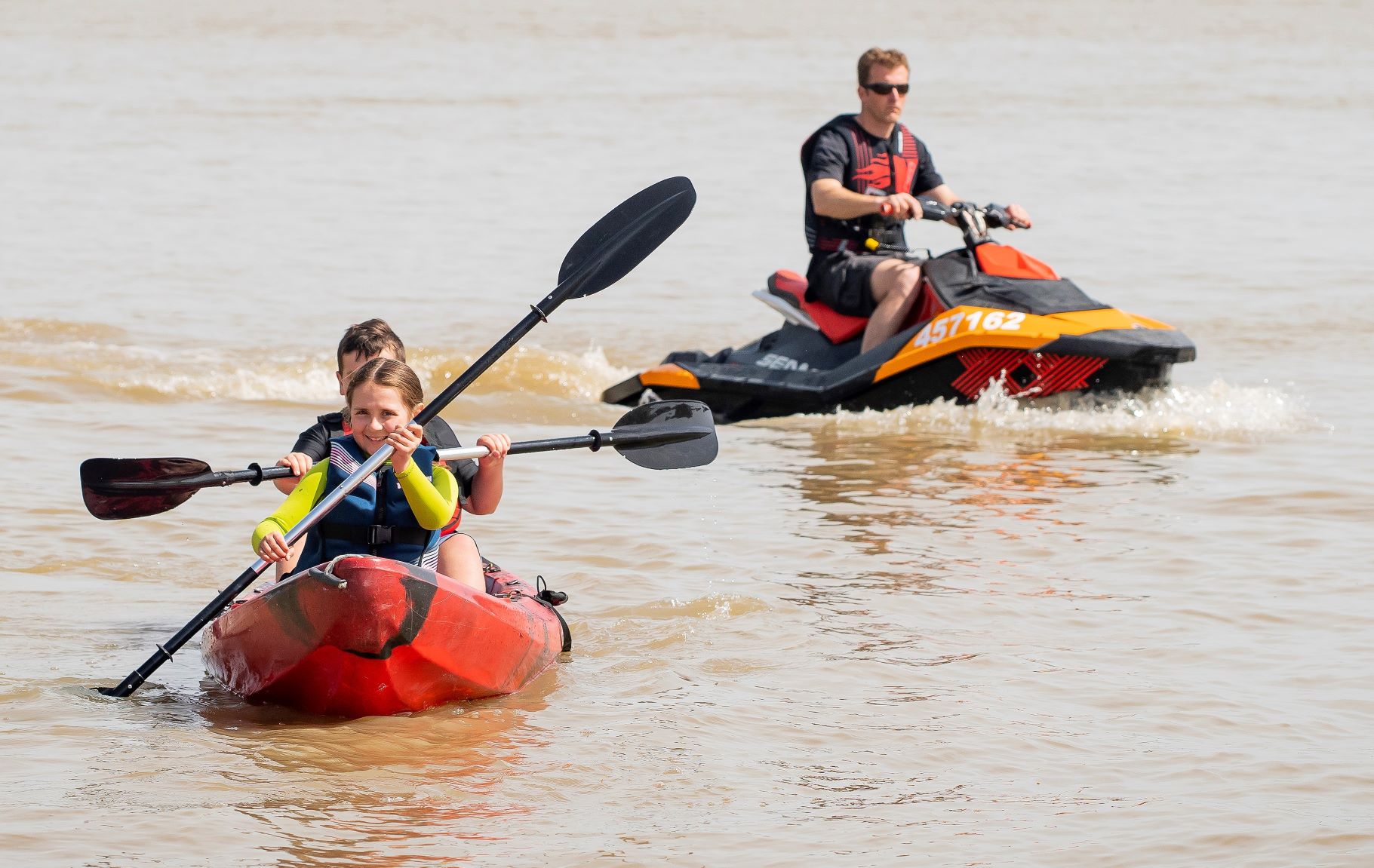 Children on a kayak with a jetski doing 4 knots in the background