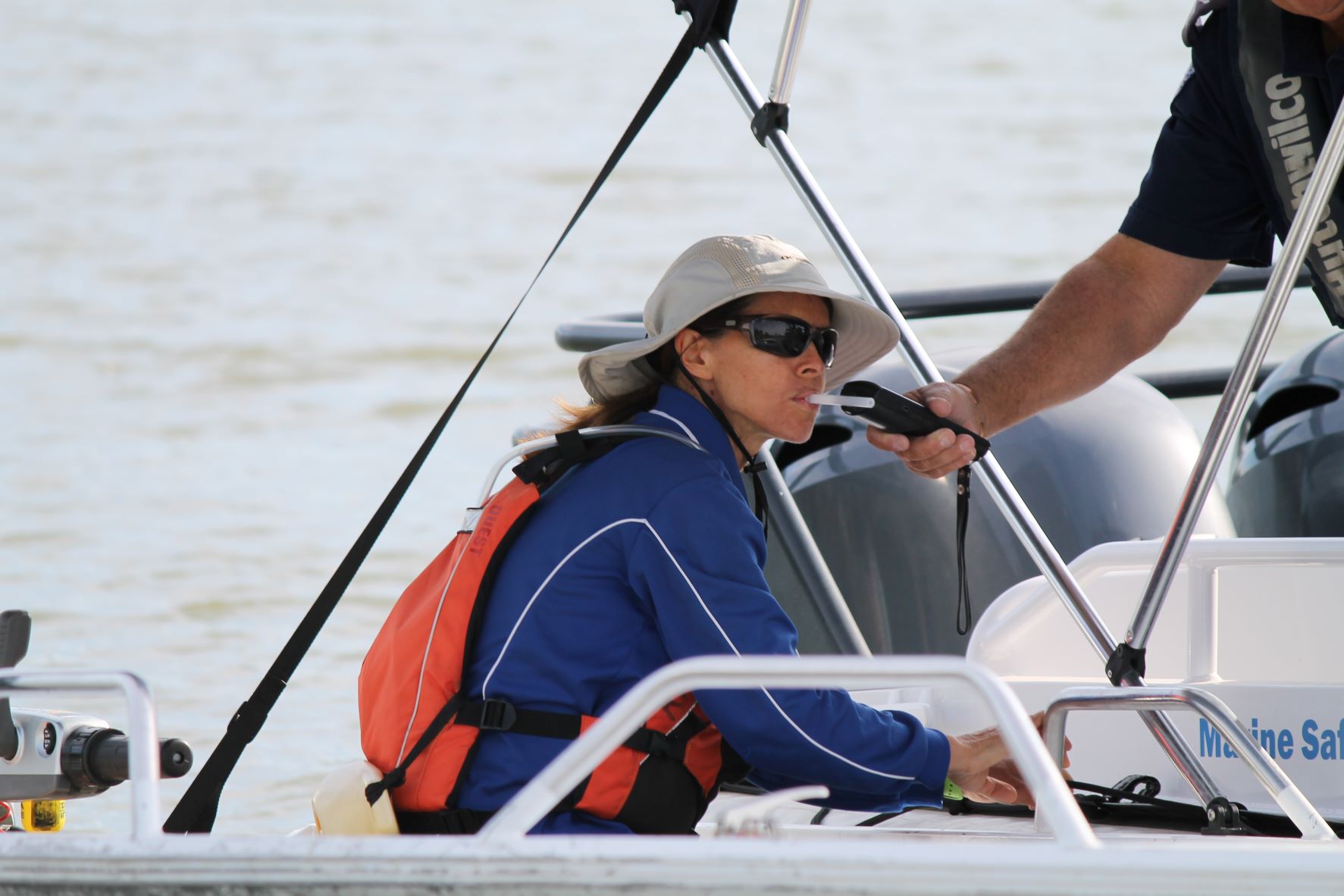 Female blowing into a blood alcohol testing device in a boat on the water