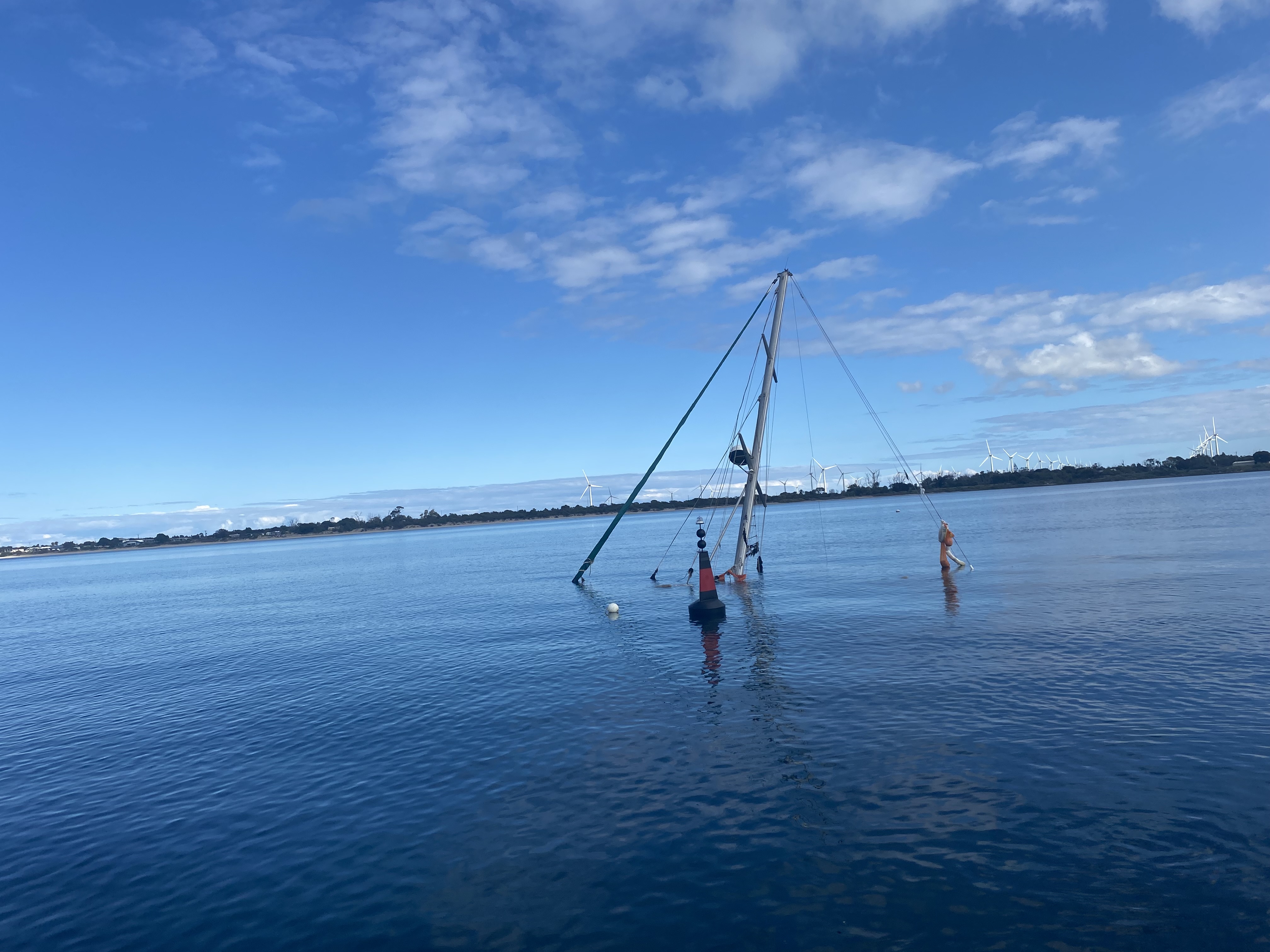 Sunken sailing vessel with mast sticking out of the water