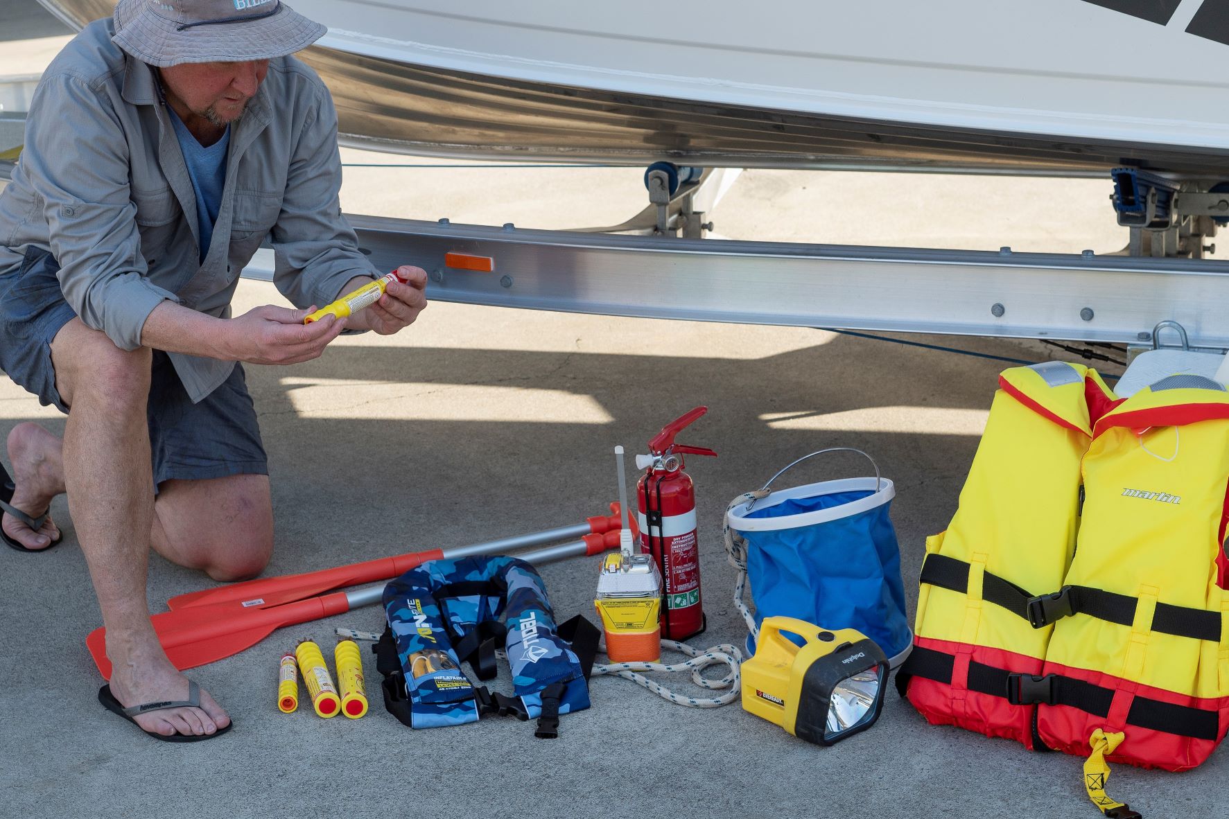 Man checking sfety equipment needed for a boat in front of a boat on land