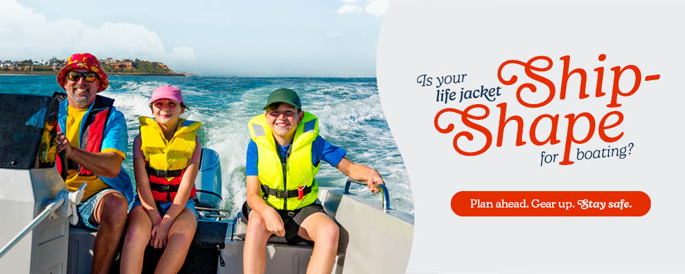 Father with his daughter and son on a boat travelling on water with coastline behind them