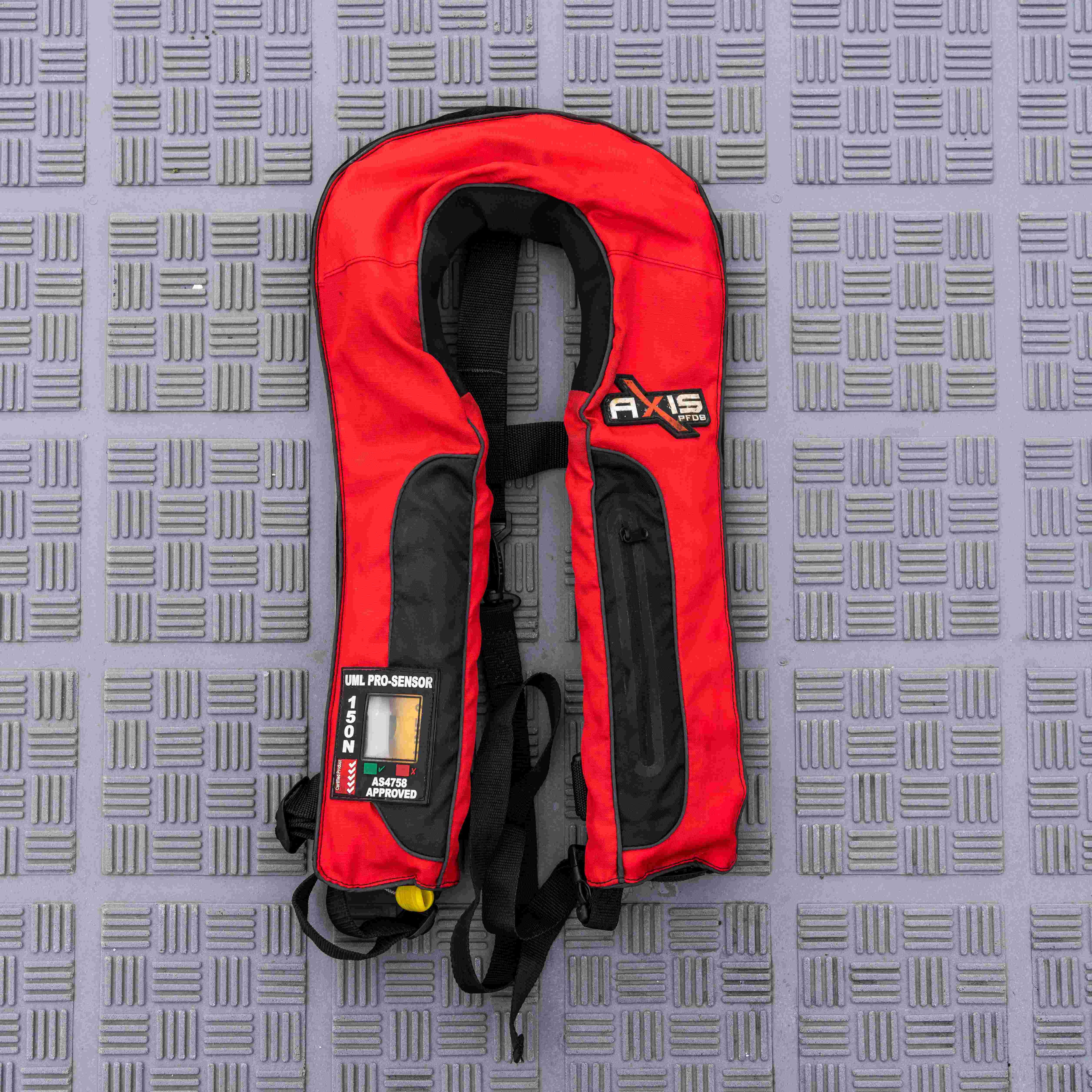 Red inflatable lifejacket laying flat on a grey background with the standard AS4758 showing