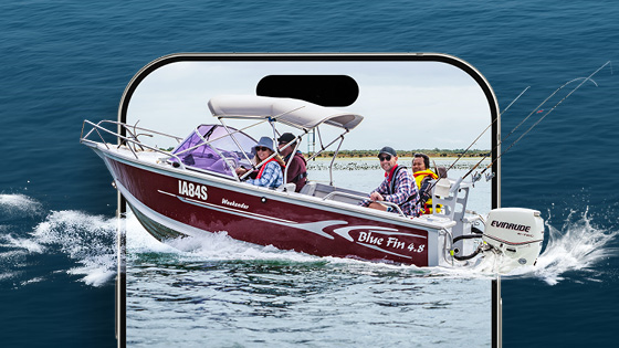 Pictured is a boat in the water with four people on board the boat. They are all wearing lifejackets smiling at the camera