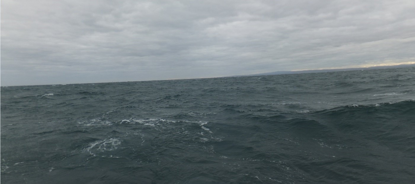 Pictured is a dark, cold, weathered day where the water is dark and choppy and the clouds in the sky are dark and gloomy.