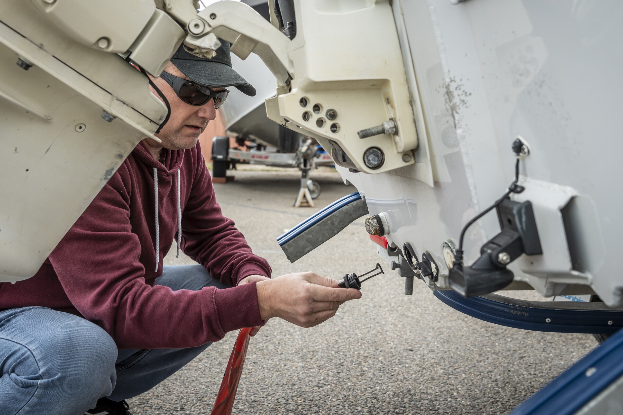 Photo captured of a man crouched down checking to make sure his bungs are in securely on his vessel.